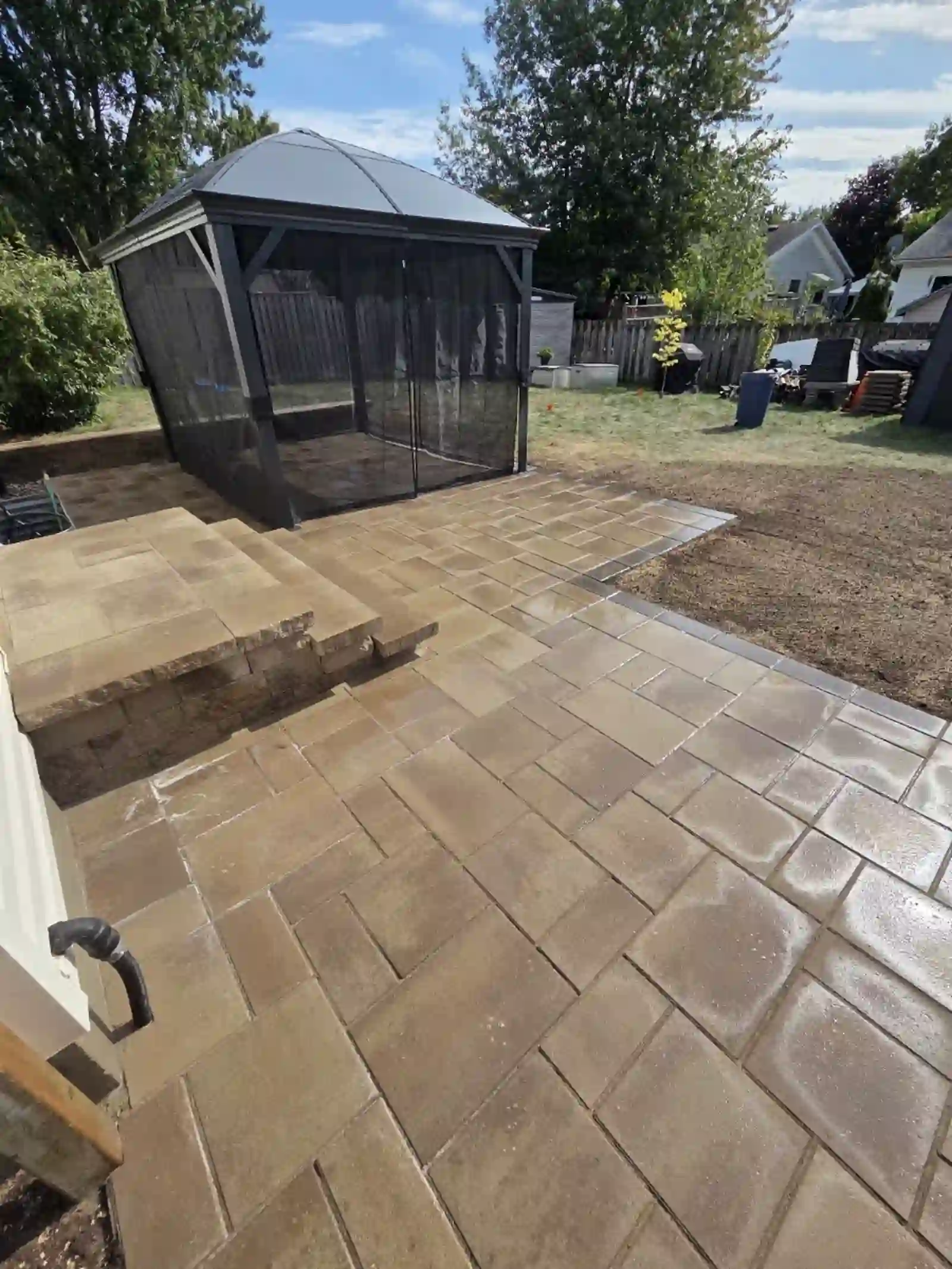 Tan interlock patio with gazebo and stone steps